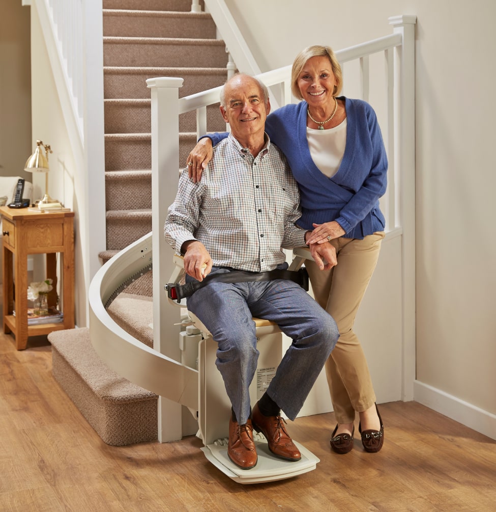 Man sitting on curved stairlift to go around corner up stairs