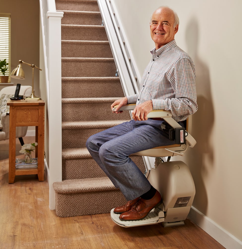 Man at bottom of stairs on stair lift