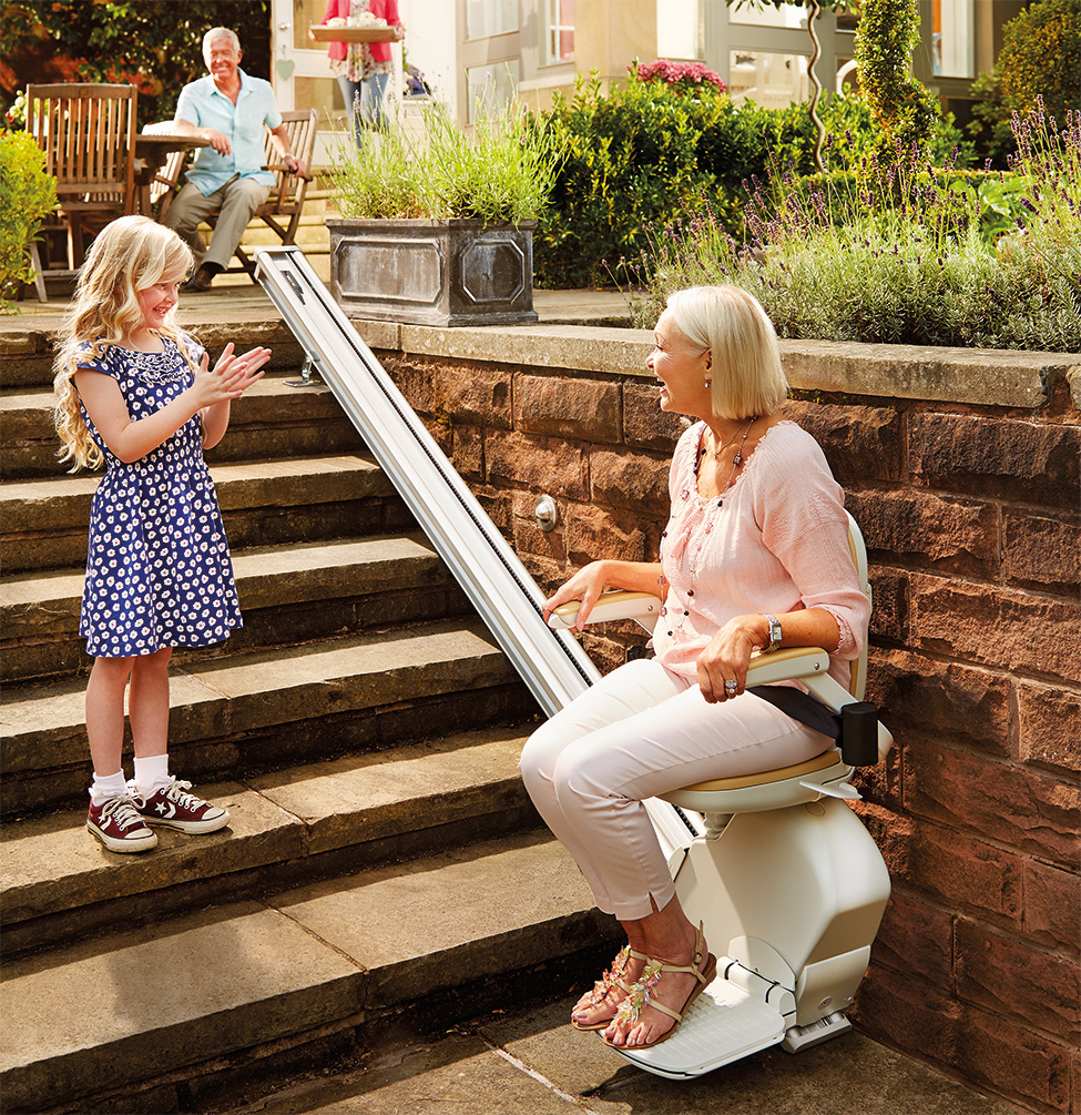 Lady with child outside clapping at her using the outdoor stairlift